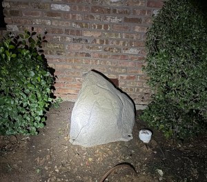 Decorative faux rock cover for outdoor water softener installation in DFW backyard — conceals buried water treatment equipment while blending into landscaping.